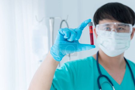 Photo for Doctor holding sample of blood testing. Doctor wearing respiratory mask and holding the Coronavirus Covid-19 blood sample. - Royalty Free Image