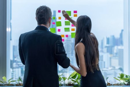 Photo for Business people working and use post it notes to share idea on the glass window in office. Businessman and Businesswoman work on project planning board. - Royalty Free Image