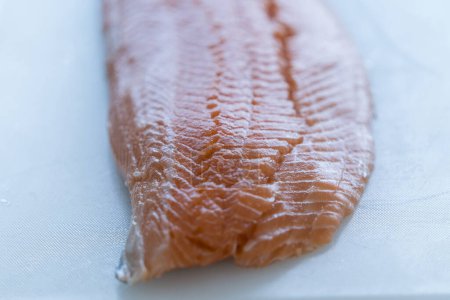 Téléchargez les photos : Tranche de poisson en gros plan sur ardoise. Filet de saumon frais sur planche à découper noire. - en image libre de droit