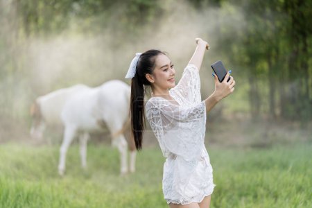 Foto de Una hermosa mujer joven usando el teléfono móvil en la hierba. Al aire libre modelo femenino sesión de fotos en la primavera. Espacio para texto. - Imagen libre de derechos