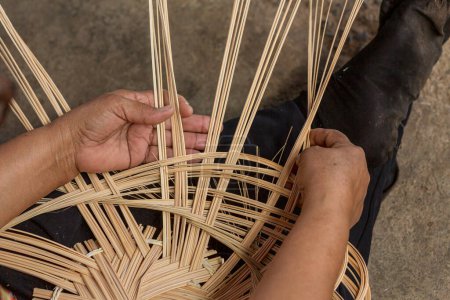 La mujer teje canasta. Mujer artesanía artesanal tejiendo hoja de palma haciendo cesta.