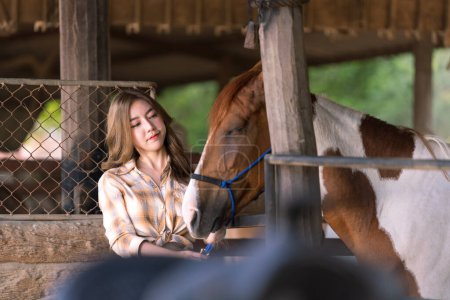 Foto de Campesina que alimenta bestias en la granja de caballos. Hermosa chica cuidando de semental. Caballo hembra y hermoso. - Imagen libre de derechos