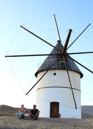 Téléchargez les photos : Parents et leur petit enfant posant devant un moulin à vent dans le village El Pozo de los Frailes, dans le parc national de Cabo de Gata, Nijar, Andalousie, Espagne. - en image libre de droit