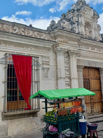 Foto de Antigua, Guatemala - November 16th of 2022: Detail of local vendor wagon in front of a wooden entrance of an old house close to San Jose Cathedral and San Carlos university. - Imagen libre de derechos