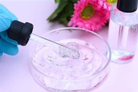 Foto de Producto de belleza, sustancias utilizadas para el tratamiento o mejora de la belleza médica, flor y fondo rosa - Imagen libre de derechos