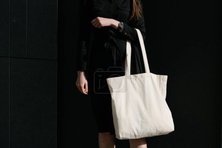 Téléchargez les photos : Femme tenant sac éco textile blanc sur fond urbain. Concept d'écologie ou de protection de l'environnement. Sac écologique blanc pour maquettes
. - en image libre de droit