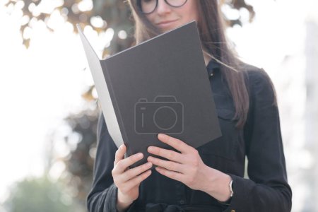 Téléchargez les photos : Couverture de livre noir entre les mains de la femme. Couverture de livre pour maquette - en image libre de droit