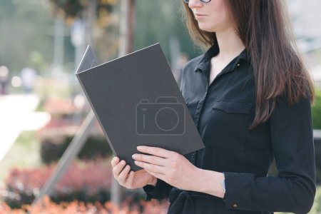 Téléchargez les photos : Couverture de livre noir entre les mains de la femme. Couverture de livre pour maquette - en image libre de droit
