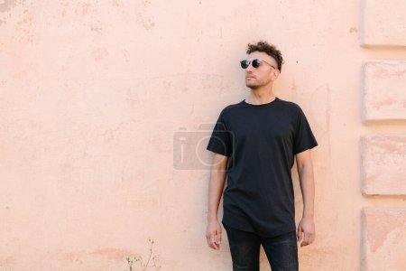 Photo for Hipster handsome male model wearing black blank t-shirt with space for your logo or design in casual urban style - Royalty Free Image