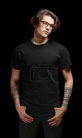 Modelo hombre con gafas con camiseta en blanco negro y jeans negros aislados sobre fondo negro
