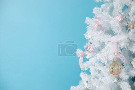 Photo for Christmas card with white christmas tree with beautiful decorations and toys. Artificial tree on blue background with copy space, place for text. Happy new year, holiday symbol, winter miracle. - Royalty Free Image