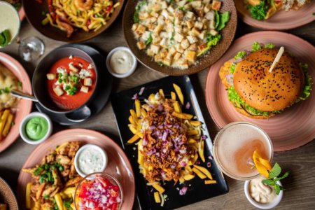 Photo for Table full of delicious food in plates top view. Fries, soup, salad, burger, sauces and drinks on festive dinner for event celebration. Nourishing food, menu of restaurant, beautiful serving food. - Royalty Free Image