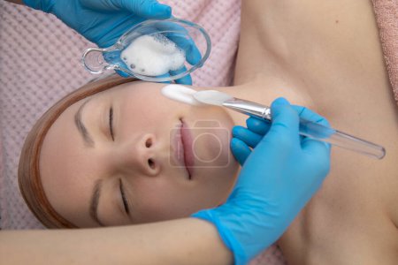 Photo for Close up cropped female patient, lying on side, getting white benzoyl peroxide powder foam, facial chemical preparation of cream lotion. Beauty treatment of acne and dermatitis problem. Skin care - Royalty Free Image