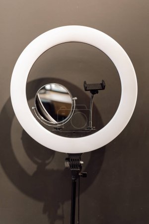 Nahaufnahme von Ring-LED-Lampe mit Telefonhalterung, Spiegel für professionelle Beauty-Blogging Vlog Streaming-Aufnahme auf grauem Hintergrund. Make-up-Anleitung, Selfie, Technik, Fotografie, Youtube. Vertikal.
