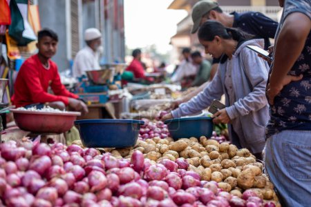 Téléchargez les photos : Goa, Inde, février 2023. Gros plan des étals pleins de légumes frais pommes de terre, oignons rouges avec des bassins en plastique bleu à vendre au bazar indien de marché de rue local en plein air entre vendeurs et acheteurs. - en image libre de droit