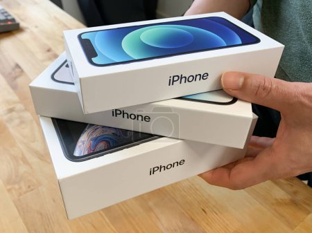 Téléchargez les photos : Femme tenant une pile d'iPhones Apple dans des boîtes. iPhone 14 Pro, 12 et XR. - en image libre de droit