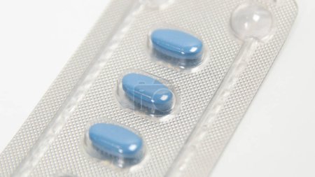 Blaue Pillen zur Behandlung von erektiler Dysfunktion oder Impotenz, in Folie auf einem weißen Tisch. Nahaufnahme.