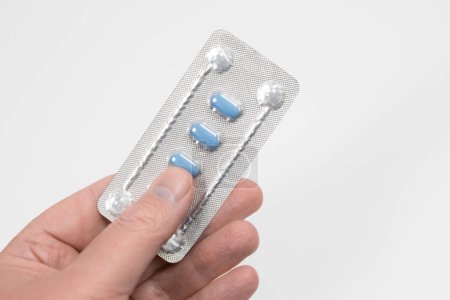 Blaue Pillen zur Behandlung von erektiler Dysfunktion oder Impotenz, die in der Hand gehalten werden. Pillen in Folie.