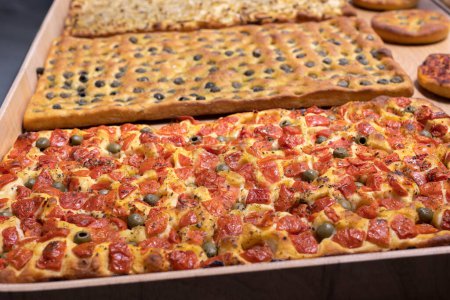Photo for Large Flatbreads displayed in Bakery filled with Oregano, Tomatoes and Olives. - Royalty Free Image