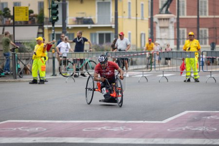 Téléchargez les photos : Athlète avec son vélo spécial sur une piste de la ville lors d'une course près de l'agent de sécurité et de contrôle de la circulation avec une pagaie. - en image libre de droit