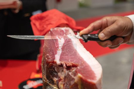 Thin Slice of Raw Ham Leg inside Cutting Holder Cut by Hand with a Sharp Knife.