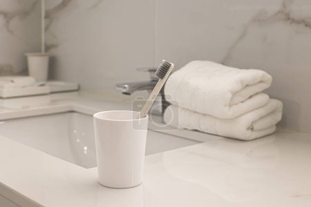 Sink and cup with toothbrushes in bathroom
