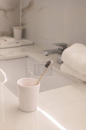 Sink and cup with toothbrushes in bathroom