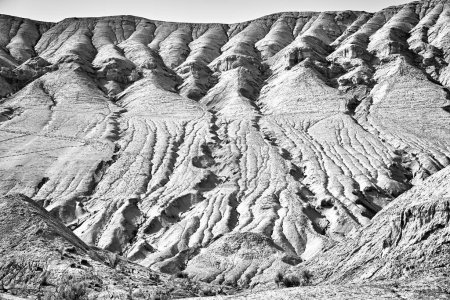 malerischer Blick auf einen Berg mit sichtbaren Schichten und Erosionsspuren im Altyn Emel Nationalpark, Kasachstan. Monochromes Foto
