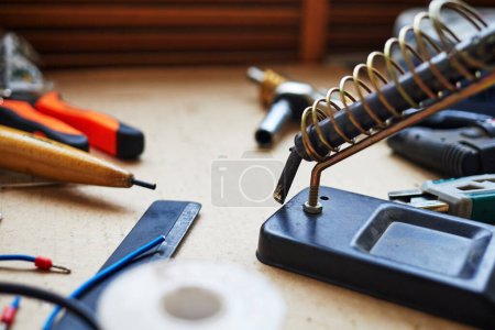 soldering iron in a spiral holder on a stand selective focus with blurred background