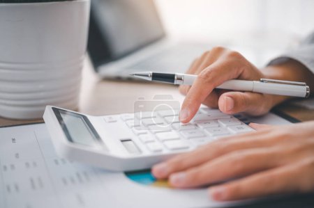 Téléchargez les photos : Close up L'homme d'affaires est assis sur une calculatrice avec un graphique dans le bureau de la comptabilité financière concept - en image libre de droit
