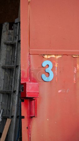 Orangerote Tür mit großer blauer Zahl 3 auf einer Industrieanlage