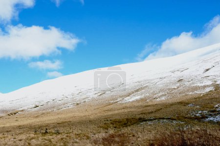 Welsh mountain winter landscape. Snow on the top of the mountains above Storey Arms in the Brecon Beacons.  Icy conditions but the sun is shining and has melted the snow of the foothills.
