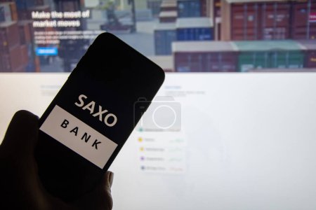 Photo for Rheinbach, Germany  26 February 2023,  The brand logo of the Danish online broke "Saxo Bank" on the display of a smartphone in front of the website (focus on the brand logo) - Royalty Free Image
