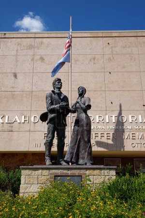 Foto de Guthrie, Oklahoma - 16 de septiembre de 2021: "La estadidad" de Fred Olds representa la boda simbólica del señor Cowboy Oklahoma y Miss Territorio Indio y se sienta frente al Museo Territorial de Oklahoma. - Imagen libre de derechos