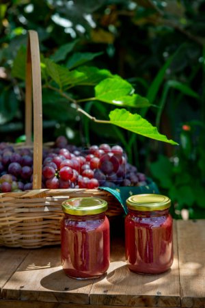 Photo for Beautiful basket full of fresh grapes with 2 jars of grape jam in front, jars without labe - Royalty Free Image