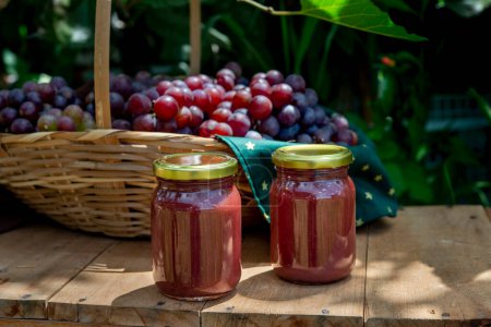 Photo for Beautiful basket full of fresh grapes with 2 jars of grape jam in front, jars without labe - Royalty Free Image
