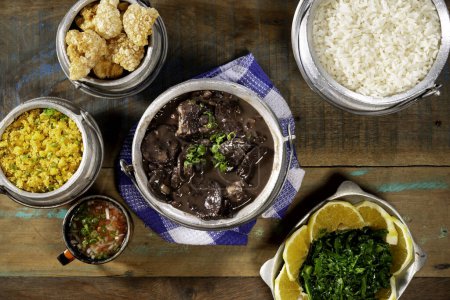Typical Brazilian dish feijoada based on black beans and pork with crakloing, rice and orange
