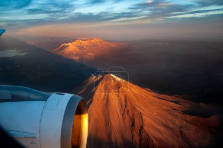 view from a airplane window of a non-active volcano, part os wing and turbine visible