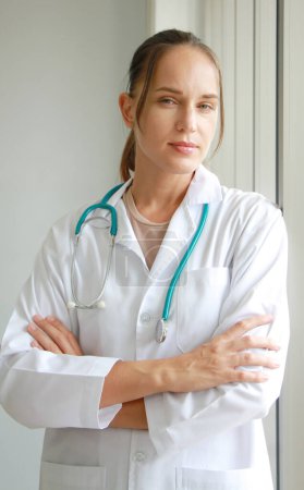 Photo for Professional Caucasian doctor woman in Gown uniform with stethoscope is standing and smiling portrait near glass wall in hospital and clinic center - Royalty Free Image