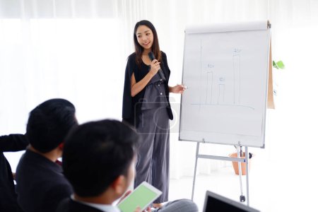 Photo for Asian woman Lecturer is lecturing about business and stock market topics and businesspeople are build powerful for success in the knowledge in the economics class in meeting room at university - Royalty Free Image