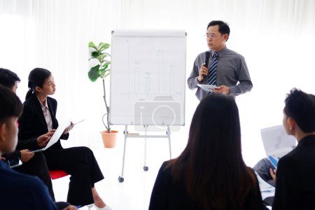 Photo for Senior Asian Lecturer is speaking about business and stock market topics and business people are having a seminar and interested in the knowledge in the economics class in meeting room at university - Royalty Free Image