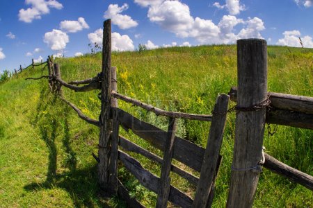 Photo for Wooden fence on the green hills against the blue sky. - Royalty Free Image