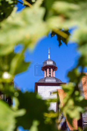 Photo for Town hall tower with carillon in the historic old town of Heppenheim in southern Germany seen through a wreath of leaves - Royalty Free Image