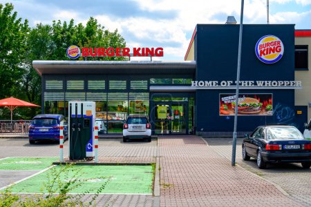 Téléchargez les photos : Berlin, Allemagne - 6 août 2021 : Entrée d'un fast-food et d'une borne de recharge pour voitures électriques dans son parking. - en image libre de droit