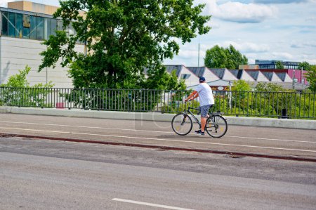 Foto de Berlín, Alemania - 30 de julio de 2023: Escena callejera con ciclista en Berlín. El carril bici fue pintado para dar a los ciclistas más espacio en el tráfico. - Imagen libre de derechos