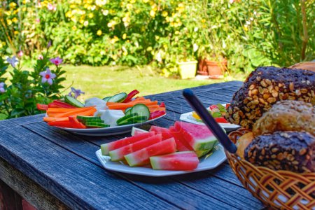 Téléchargez les photos : Table de petit déjeuner en bois dans le jardin avec divers éléments nutritifs. - en image libre de droit