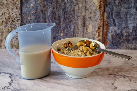 Repas du matin avec un bol de flocons d'avoine et noix. À côté se trouve une cruche de lait.