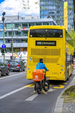 Téléchargez les photos : Berlin, Allemagne - 27 avril 2024 : Courrier à vélo pour la nourriture derrière un bus de transport public dans le centre de Berlin. - en image libre de droit