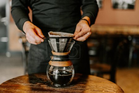Professioneller Barista bereitet Kaffee mit Chemikalien über Kaffeemaschine und Wasserkocher zu
