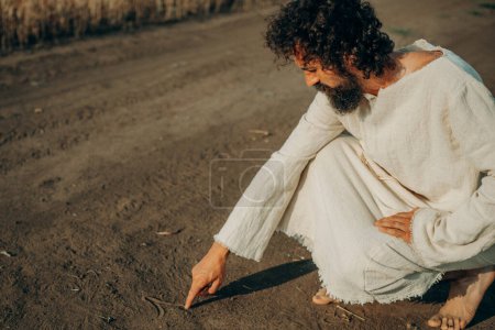 Foto de Guión Divina: El dedo de Jesús en la arena - Imagen libre de derechos